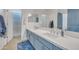 Bathroom featuring a double vanity with quartz countertop, blue cabinets, and a separate shower room at 7129 S Stadium Way, Gilbert, AZ 85298
