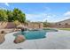 In-ground pool features stone waterfall, palm trees, and a concrete patio at 7129 S Stadium Way, Gilbert, AZ 85298