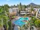 Community pool with lounge seating surrounded by palm trees, lush green landscaping, and mountain views at 7625 E Camelback Rd # 310B, Scottsdale, AZ 85251
