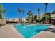 Large community pool surrounded by palm trees, lounge chairs, and well-maintained landscaping at 7625 E Camelback Rd # 310B, Scottsdale, AZ 85251