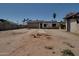 View of the backyard with a concrete pathway, dirt, and palm trees at 7930 E Broadway Rd, Mesa, AZ 85208