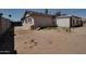 Exterior view of a stucco house with an undeveloped yard and palm trees in the background at 7930 E Broadway Rd, Mesa, AZ 85208