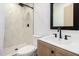 Modern bathroom features tile shower and a wood vanity with a black framed mirror at 927 E Greenway Rd, Phoenix, AZ 85042