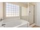 Bathroom showcasing a separate shower and a bathtub under a glass block window at 12426 W Adams St, Avondale, AZ 85323