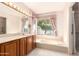 Bathroom featuring a vanity, large mirror, tub with jets, and views of the outdoors at 1258 E Granada St, Mesa, AZ 85203