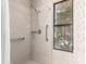 Updated shower with stone tile, modern fixtures, grab bars, and a window at 1258 E Granada St, Mesa, AZ 85203
