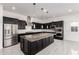 Spacious kitchen featuring dark cabinets, an oversized island, stainless appliances, and modern lighting fixtures at 14177 W Calle Lejos --, Surprise, AZ 85387