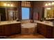 Luxurious bathroom with dual vanities, a soaking tub, decorative tile accents, and natural light at 14725 S 182Nd Dr, Goodyear, AZ 85338