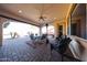 Outdoor covered patio with brick flooring, dining table set, ceiling fan, and comfortable seating area for entertaining at 14725 S 182Nd Dr, Goodyear, AZ 85338