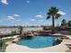 Beautiful swimming pool with rock waterfall feature, surrounding palm trees, and desert landscape at 14725 S 182Nd Dr, Goodyear, AZ 85338