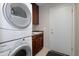Convenient laundry area with stacked washer and dryer and dark wood cabinets for storage at 15550 N Frank Lloyd Wright N Blvd # 1040, Scottsdale, AZ 85260