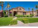 Elegant two-story home featuring a lush lawn, mature palm trees, and attractive desert landscaping at 1808 S Sailors Way, Gilbert, AZ 85295