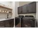 Laundry room features side-by-side washer and dryer, dark wood cabinets, and open shelving at 1808 S Sailors Way, Gilbert, AZ 85295