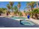 Inviting backyard pool and spa area surrounded by travertine tiling, lush landscaping, and a calming waterfall feature at 1808 S Sailors Way, Gilbert, AZ 85295