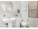Cozy half bath featuring pedestal sink, round mirror, framed art and toilet at 18903 N Shelby Dr, Maricopa, AZ 85138