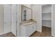 Bathroom featuring a granite countertop, white cabinetry, vanity mirror and access to a walk-in closet at 18916 W Laurel Ln, Surprise, AZ 85388
