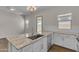 Open kitchen with white cabinets, granite countertops, stainless steel appliances, and wood-look tile flooring at 18916 W Laurel Ln, Surprise, AZ 85388