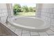 Bathroom featuring a soaking tub, large window with backyard views and tiled surround at 19006 E Karsten Dr, Queen Creek, AZ 85142