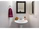 Bright powder room featuring a pedestal sink, decorative mirror, and a burgundy towel at 2004 E Heartwood Ln, Phoenix, AZ 85022