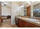 Bathroom features a dual sink vanity with wood cabinets and tile countertop, plus a view of the shower at 21205 E Excelsior Ave, Queen Creek, AZ 85142