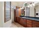 Bright primary bathroom features a large vanity with granite countertop, wood cabinets, walk-in shower, and glass block window at 21205 E Excelsior Ave, Queen Creek, AZ 85142