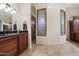 Elegant primary bathroom offers dual sinks, granite countertops, wood cabinets and a walk-in shower with glass block window at 21205 E Excelsior Ave, Queen Creek, AZ 85142