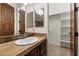 Bathroom features a single sink vanity with wood cabinets and tile countertop, plus a view of the closet at 21205 E Excelsior Ave, Queen Creek, AZ 85142