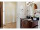 Charming powder room with dark wood vanity, granite countertop, decorative mirror, and access to the hallway at 21205 E Excelsior Ave, Queen Creek, AZ 85142
