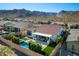 Expansive aerial view of a home with a pool, covered patio, and lush landscaping, set against a majestic mountain backdrop at 21449 W Mariposa St, Buckeye, AZ 85396