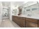 Bright bathroom featuring a long vanity with double sinks, white countertop and large mirror reflecting tiled shower at 21449 W Mariposa St, Buckeye, AZ 85396