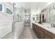 Bright bathroom with a long vanity, white countertops, and tiled walk-in shower with dual shower heads at 21449 W Mariposa St, Buckeye, AZ 85396