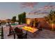 Inviting backyard with a cozy fire pit and Adirondack chairs under a colorful evening sky near the pool at 21449 W Mariposa St, Buckeye, AZ 85396