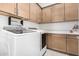 Well-equipped laundry room with modern machines and ample storage cabinets and a countertop at 21449 W Mariposa St, Buckeye, AZ 85396