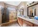 Bathroom featuring a walk-in shower and double vanity with framed mirrors, granite countertops, and wood cabinets at 2156 W Periwinkle Way, Chandler, AZ 85248