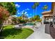 A sparkling pool with a lush green lawn, mature trees, and a serene spa provides a backyard oasis at 2156 W Periwinkle Way, Chandler, AZ 85248