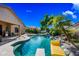 Refreshing backyard pool with a rock waterfall, slide, and lush landscaping, perfect for summer relaxation at 2156 W Periwinkle Way, Chandler, AZ 85248