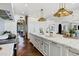 Spacious white kitchen with marble island, brass pendant lighting, herringbone floors and open access to other rooms at 2339 E Virgo Pl, Chandler, AZ 85249