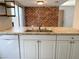 Kitchen featuring stainless steel sink, white cabinets, breakfast bar, and brick accent wall at 244 E Ponderosa Ln, Phoenix, AZ 85022