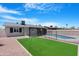 Backyard with pool, artificial turf and covered patio area, enclosed by a black wrought iron fence at 3607 N 79Th Ave, Phoenix, AZ 85033