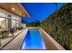 Illuminated backyard pool at dusk, surrounded by lush greenery, adjacent to outdoor seating area at 3626 N Mohave Way, Scottsdale, AZ 85251