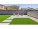 Backyard features a artificial turf lawn, concrete block walls, and a stone paver patio with firepit and chairs at 4283 W Nora Dr, San Tan Valley, AZ 85144