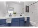 Modern bathroom with double sinks, dark blue vanity, and shower with glass doors at 45722 W Sky Ln, Maricopa, AZ 85139