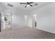 Large bedroom with neutral carpet, ceiling fan, and multiple doors leading to other rooms and bathrooms at 45722 W Sky Ln, Maricopa, AZ 85139