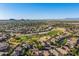 Expansive aerial view showcasing a community bordering a lush golf course and distant mountain views at 654 E Taylor Trl, San Tan Valley, AZ 85143