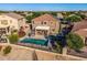 A backyard view highlighting the home, fenced pool, covered patio, plants, and desert landscaping at 654 E Taylor Trl, San Tan Valley, AZ 85143