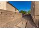 Side yard of home with gravel, mature trees, block wall and potential space for outdoor activities at 654 E Taylor Trl, San Tan Valley, AZ 85143
