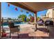 Covered patio with outdoor seating next to the backyard pool and golf course in the background at 654 E Taylor Trl, San Tan Valley, AZ 85143