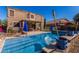 Beautiful pool with cool blue umbrellas behind a beige home exterior and clear skies at 654 E Taylor Trl, San Tan Valley, AZ 85143