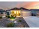 Inviting home featuring desert landscaping, a well-lit porch, and a two-car garage at 7618 S Lone Pine Pl, Gold Canyon, AZ 85118