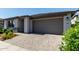 View of the garage, brick driveway, and well maintained landscaping of this stylish home at 9312 E Spiral Ave, Mesa, AZ 85212